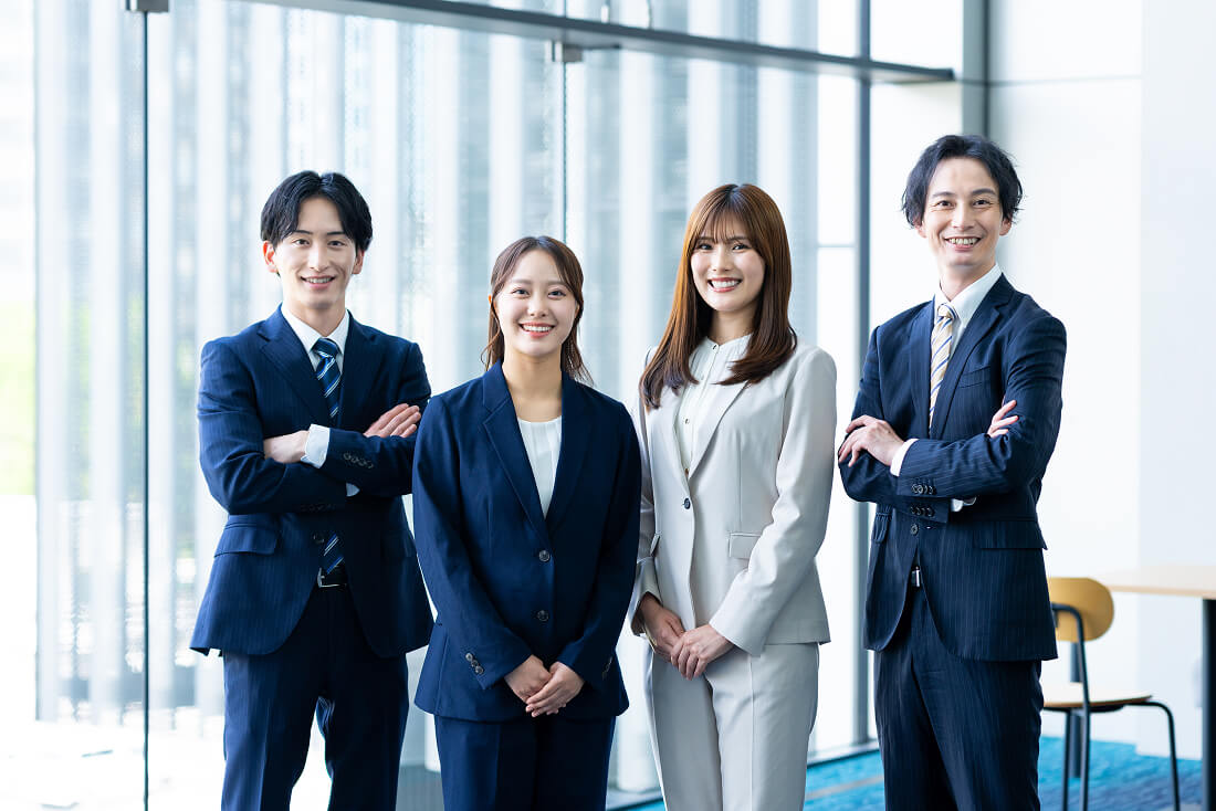 ４人のビジネスマンが横に並んで笑っている様子